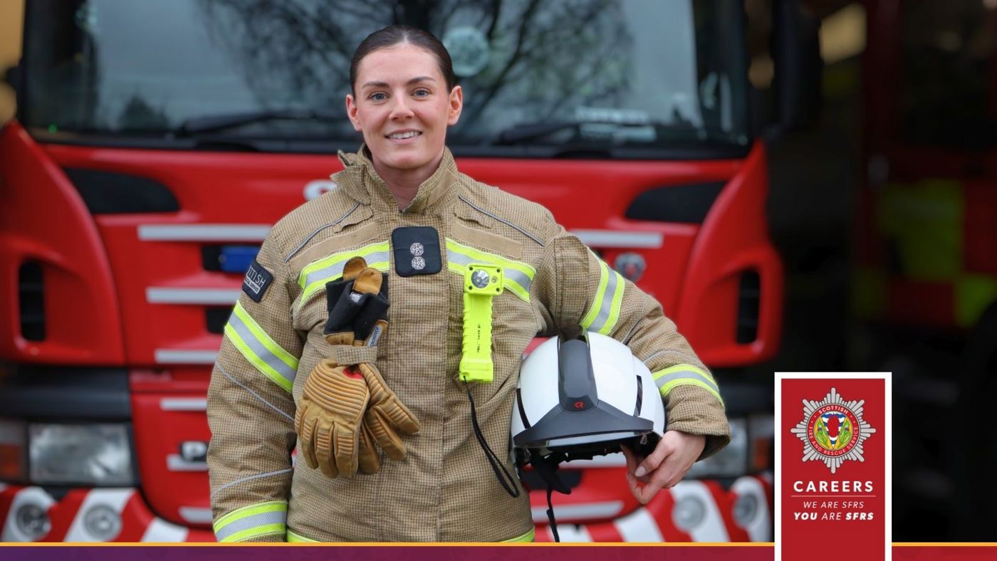 A firefighter in uniform stands proudly in front of a red fire truck, ready for action.