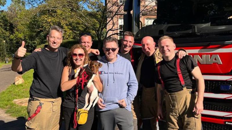 Firefighters with Still Game stars Jane McCarry and Mark Cox and their dog in front of an appliance