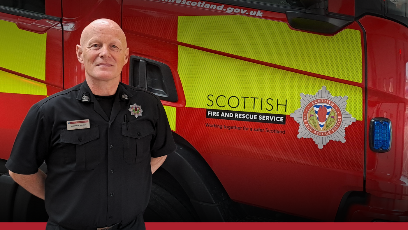 Firefighter in a black uniform standing next to a red fire engine.