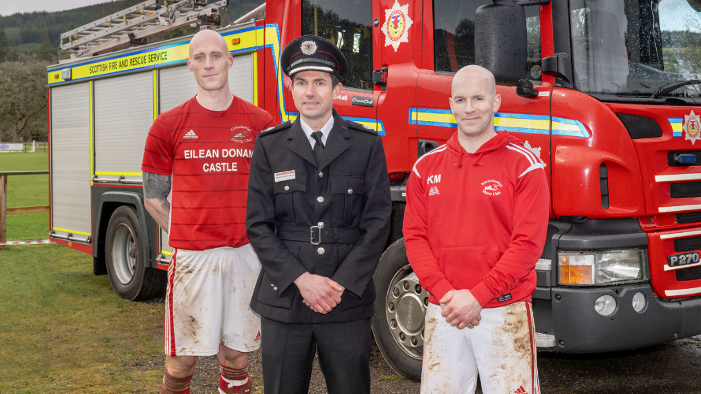 Two shinty players with fire chief
