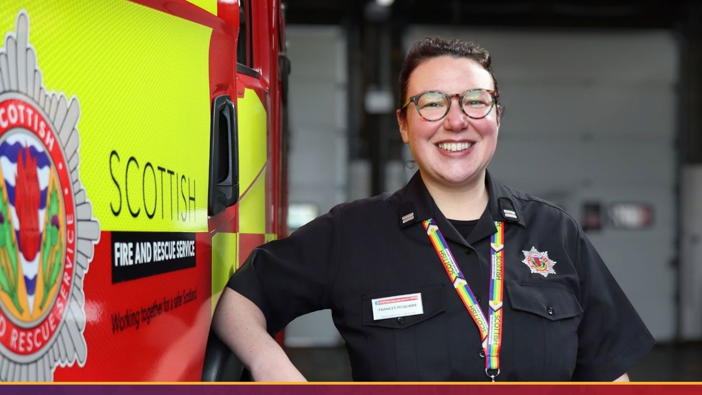 A woman in a uniform stands proudly beside a fire truck, showcasing her role in emergency services.