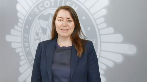 Deborah Standfield in front a grey background with the SFRS crest.