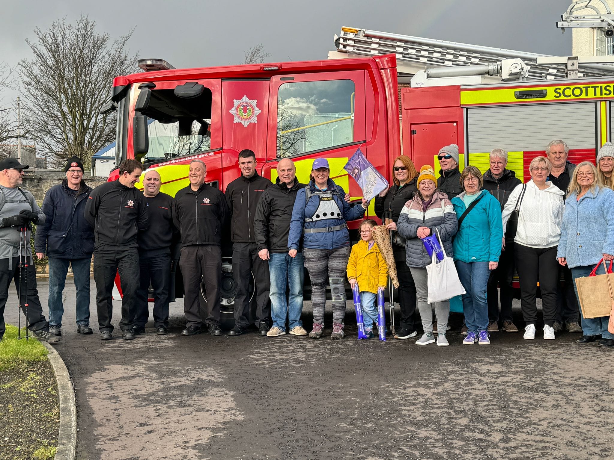 woman stands with friends and family against a fire engine