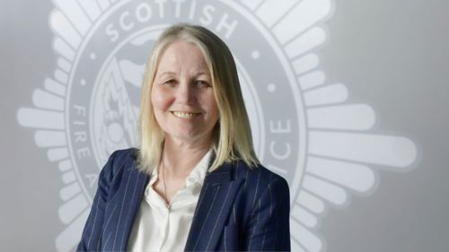 Fiona Ross in front of a grey background with the SFRS crest.