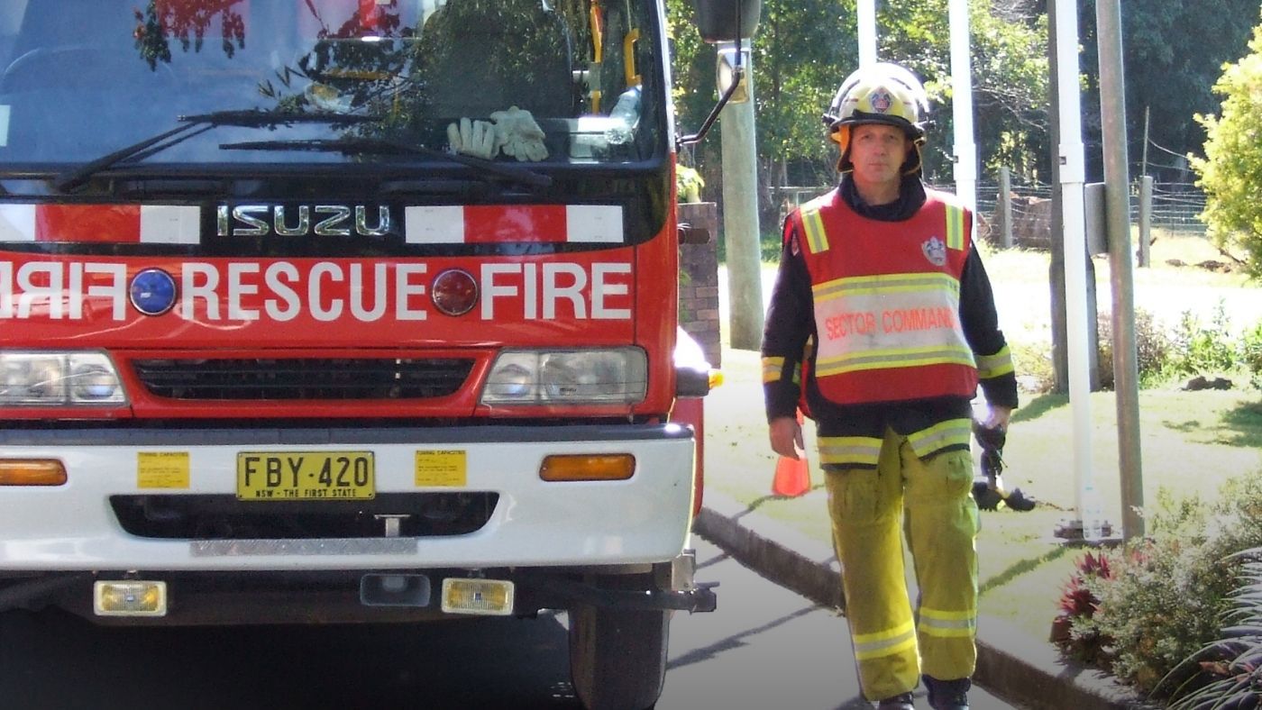 Firefighter standing alongside a fire appliance in full PPE 