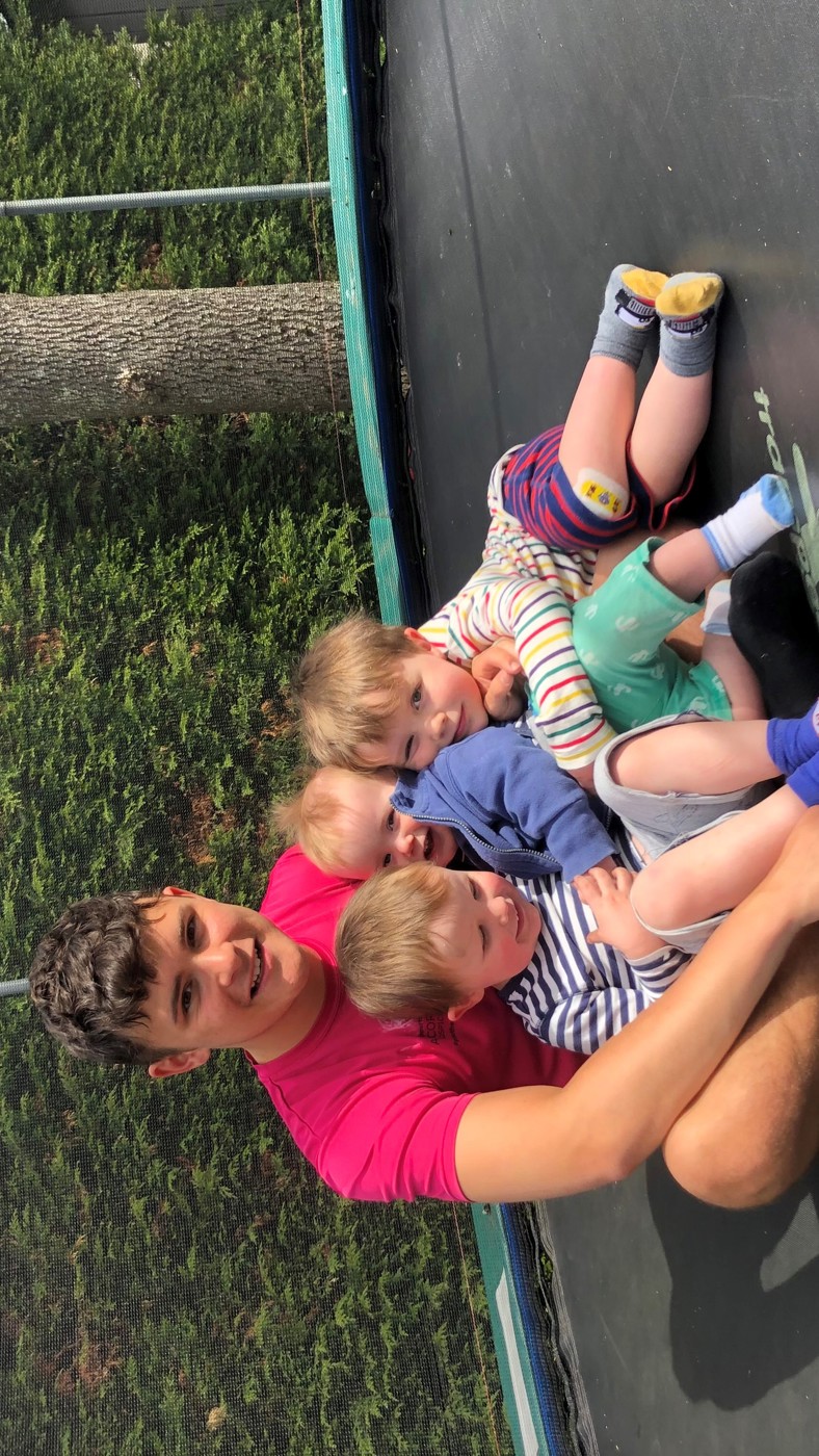 A dad with 3 children sitting on a trampoline 