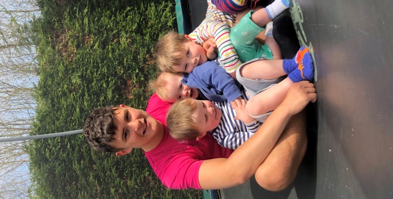 A dad with 3 children sitting on a trampoline