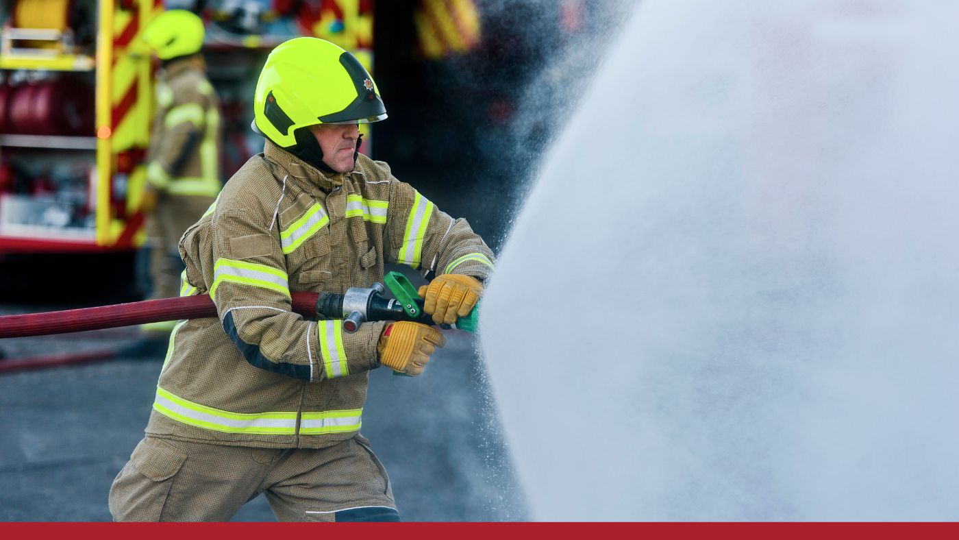 A firefighter directs water from a hose onto a fire, showcasing emergency response efforts in a critical situation.