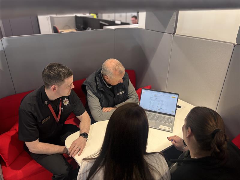 four people looking at a laptop screen
