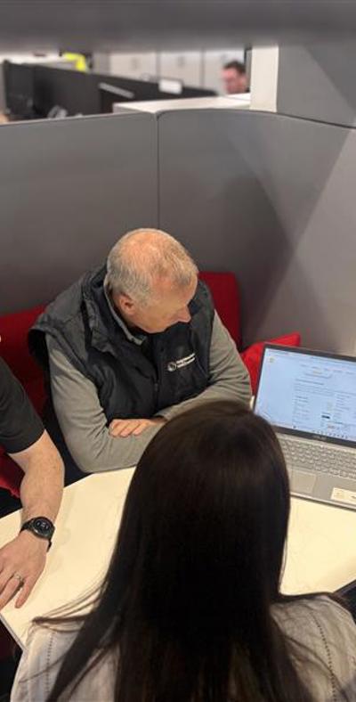 four people looking at a laptop screen