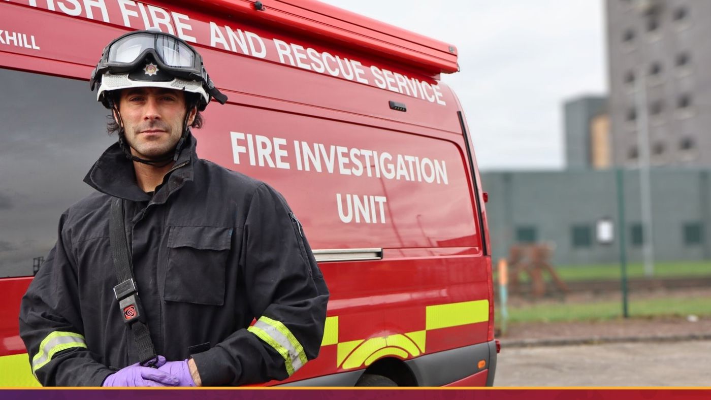 A firefighter in uniform stands proudly in front of a red fire truck, ready for action.