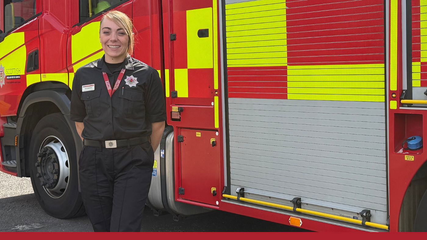 A female firefighter in uniform poses next to a fire truck, representing bravery and dedication to public safety.