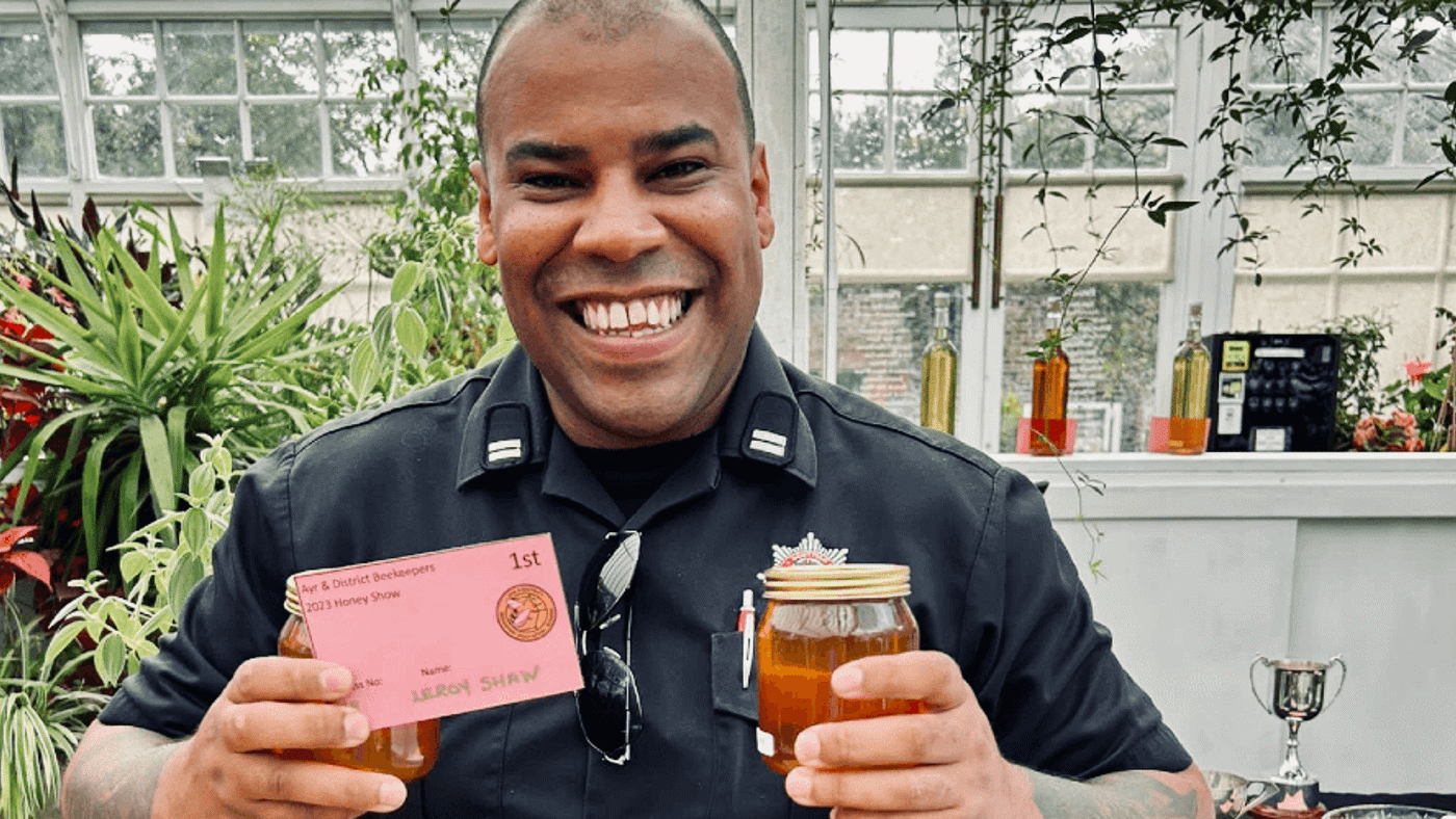Firefighter smiling with a pot of honey in hand