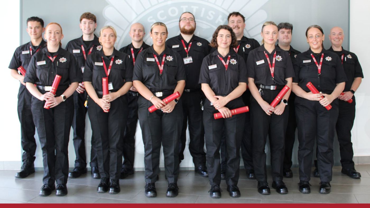 A group of individuals in black uniforms standing closely together.