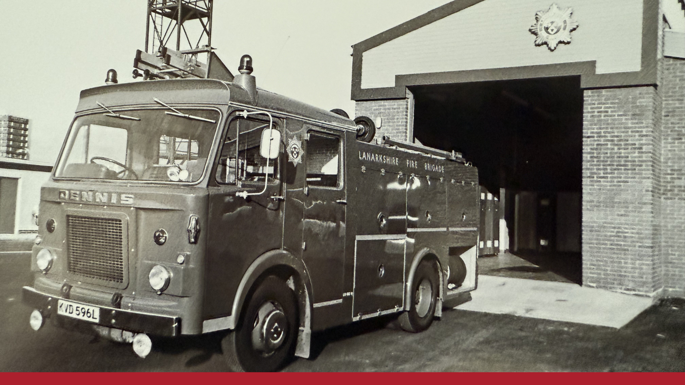 A vintage image of a fire truck stationed outside a building, highlighting its classic features and historical context.