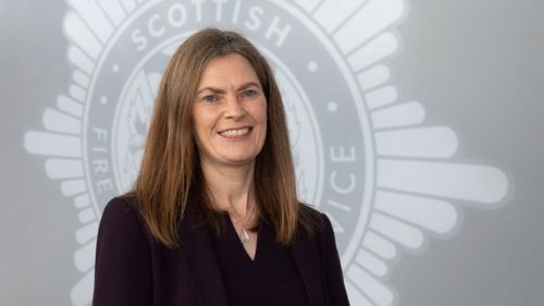 Sarah O'Donnell standing in front of a crest SFRS crest